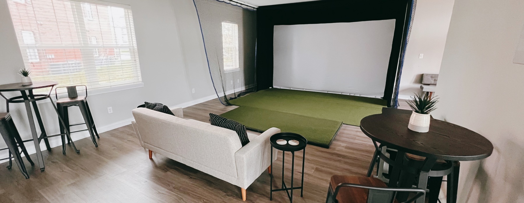 room with a golf simulator and sofa